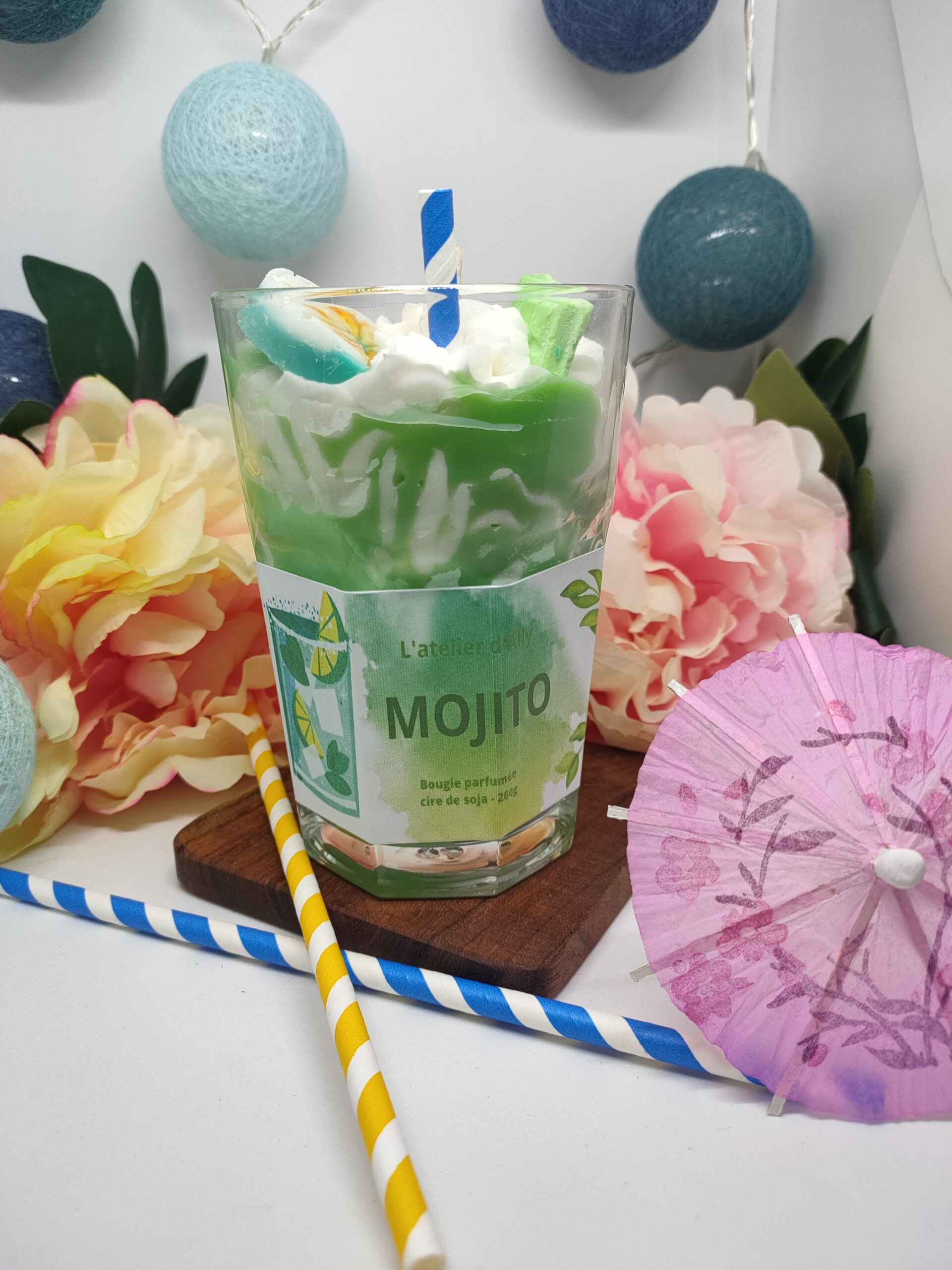 Bougie Mojito coulée dans un grand verre à cocktail, cire verte effet sirop de menthe, chantilly blanche au centre, demi- citron vert encire et paille plantée.
