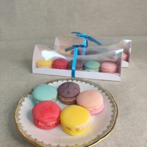 Coffret de fondants parfumés en forme de macarons artisanaux présenté sur une assiette avec sa boîte cadeau faite main