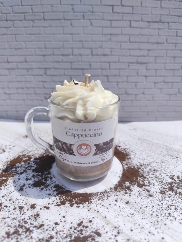 Bougie Cappuccino coulée dans une tasse en verre avec base marron, chantilly blanche au centre et chocolat en poudre saupoudré sur le dessus.