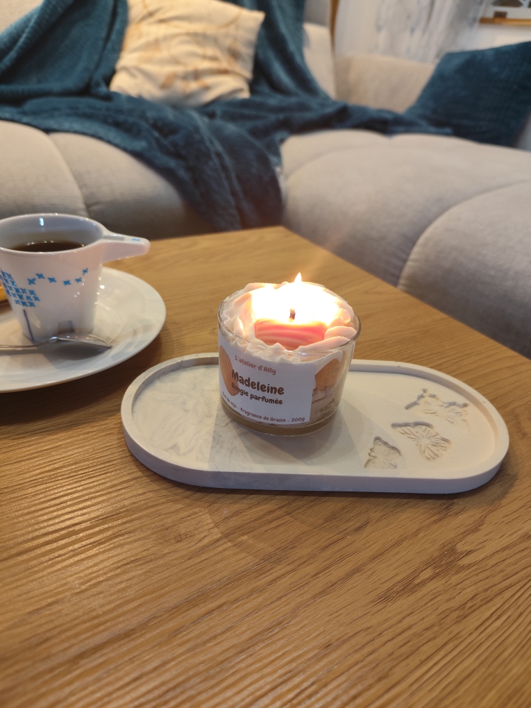 Bougie gourmande parfumée Madeleine allumée, ambiance cocooning avec café et plaid