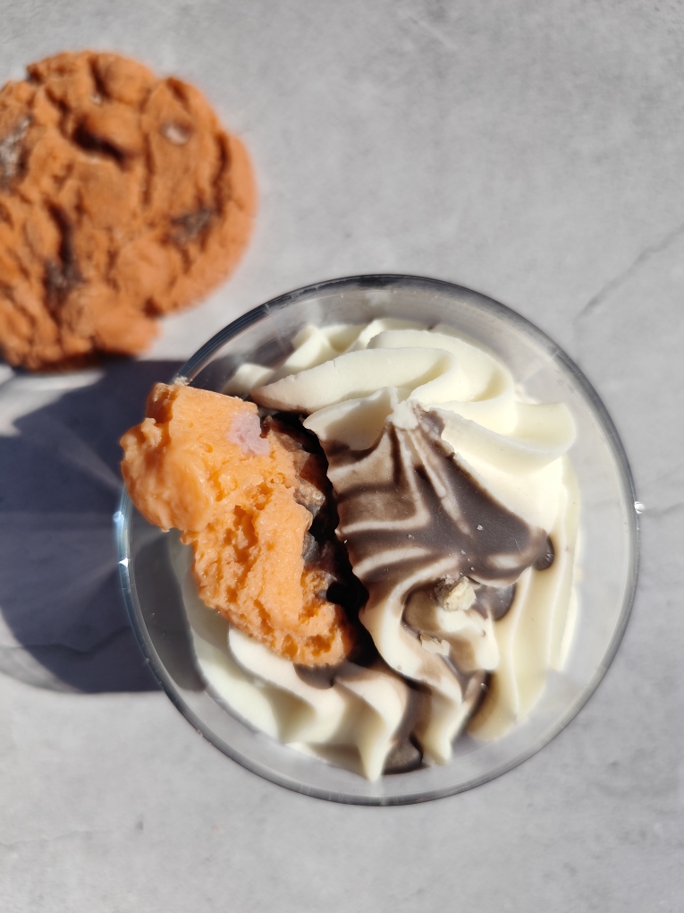 Vue de dessus de al bougie Cookie Chocolat avec cookie en cire et pépites sur la chantilly blanche. Coulis chocolat nappé dessus.