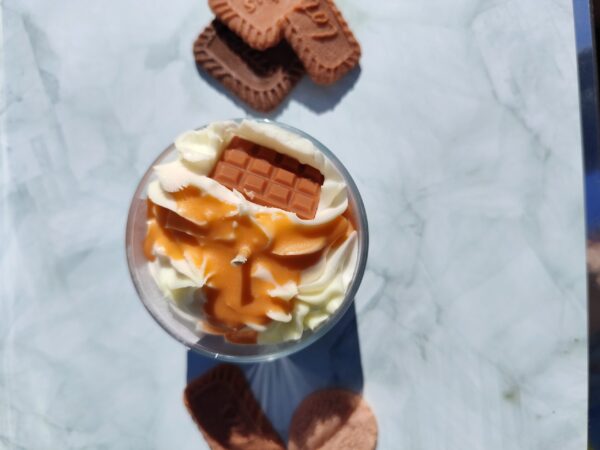Vue de dessus de la bougie Caramel Beurre Salé avec chantilly blanche, coulis de caramel coulant et tablette en cire.