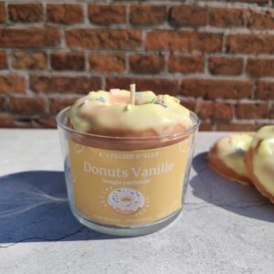 Bougie Donuts Vanille dans un pot en verre, décorée d'un donut en cire avec glaçage jaune et vermicelles colorés sur une chantilly blanche