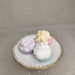 Trois mini cupcakes fondants parfumés artisanaux présentés sur une assiette sur pied.