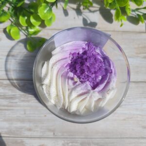 Vue de dessus de la bougie Lilas, avec chantilly blanche parsemée de paillettes colorées.