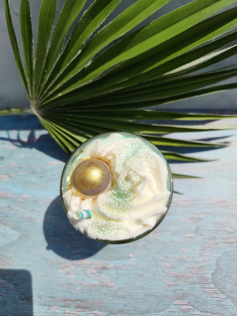 Dessus de la bougie Cocktail Coco et Citron Vert avec chantilly blanche, coulis vert, tranche de citron en cire et noix de coco dorée