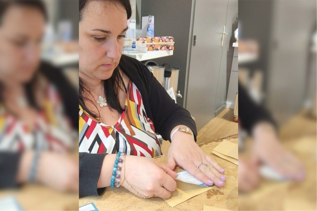 Allison de L'atelier d'Ally collant une étiquette réglementaire sur une bougie artisanale parfumée.
