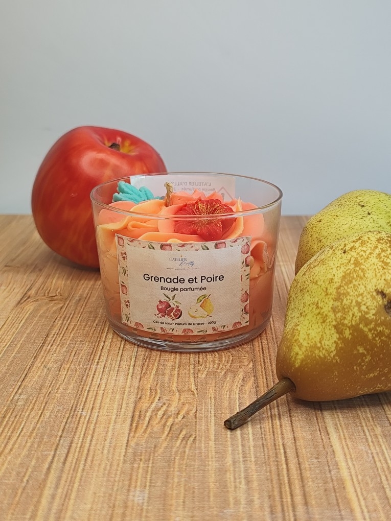 Bougie artisanale Grenade et Poire présentée avec une pomme rouge et une poire pour illustrer son univers parfumé fruité.
