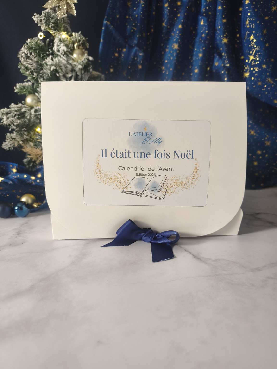Calendrier de l'Avent fondants parfumés Il était une fois Noël, coffret blanc avec illustration de livre ouvert et ruban bleu.