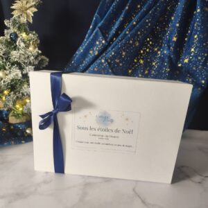 Calendrier de l'Avent Premium Sous les étoiles de Noël, coffret blanc avec ruban bleu nuit et étiquette dorée.